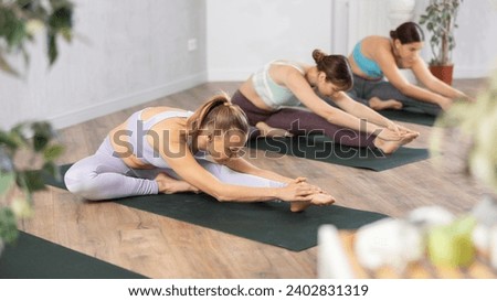 Young woman practicing stretching exercises in yoga studio