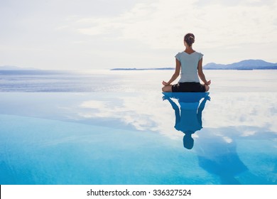 Young woman practicing yoga. Beautiful girl meditating, doing breathing exercises. Harmony, balance, meditation, relaxation, mindfulness, recreation, self care, body care, healthy lifestyle concept - Powered by Shutterstock