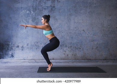 Young Woman Practicing Yoga. Chair Pose On Tip Toes.