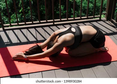 Young woman practicing yoga in downward pose in a balcony city life with used yoga mat - Powered by Shutterstock