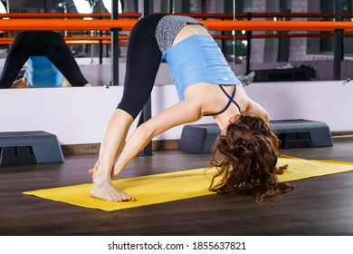 Young Woman Practicing Yoga Forward Fold In The Studio