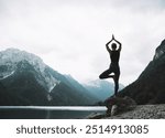 Young woman is practicing yoga at mountain lake. Girl doing yoga on nature. Healthy lifestyles. Concept of vitality, balance, mindfulness, zen energy, calmness, relaxation.