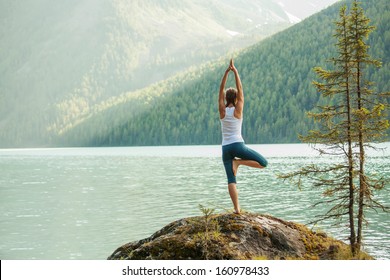 Young woman is practicing yoga at mountain lake - Shutterstock ID 160978433
