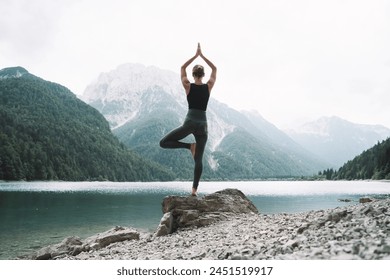 Young woman is practicing yoga at mountain lake. Girl doing yoga on nature. Healthy lifestyles. Concept of vitality, balance, mindfulness, zen energy, calmness, relaxation. - Powered by Shutterstock