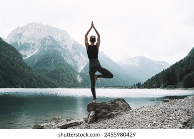 Young woman is practicing yoga at mountain lake. Girl doing yoga on nature. Healthy lifestyles. Concept of vitality, balance, mindfulness, zen energy, calmness, relaxation. - Powered by Shutterstock