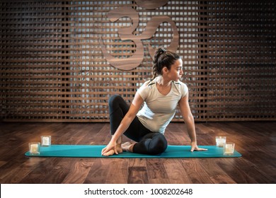 Young Woman Practicing Yoga On Exercise Mat With Candles.