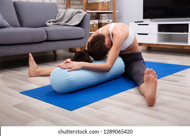 Young Woman Practicing Yoga On Bolster At Home