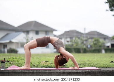 Young Woman Practicing Yoga Outdoors in a Park on a Sunny Day, Performing a Backbend Pose on a Pink Mat - Powered by Shutterstock