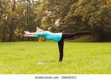 Young woman practicing yoga in the park.Yoga-Virabhadrasana III /Warrior Pose III
