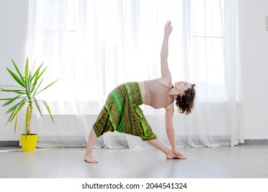 Young woman practicing yoga, standing in Utthita Trikonasana exercise, extended triangle pose