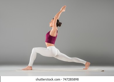young woman practicing yoga, standing in Warrior one exercise, Virabhadrasana I pose
