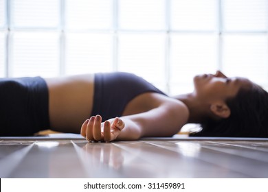 Young woman practicing in a yoga studio. Shavasana or corps pose is the end of a class or practice. - Powered by Shutterstock
