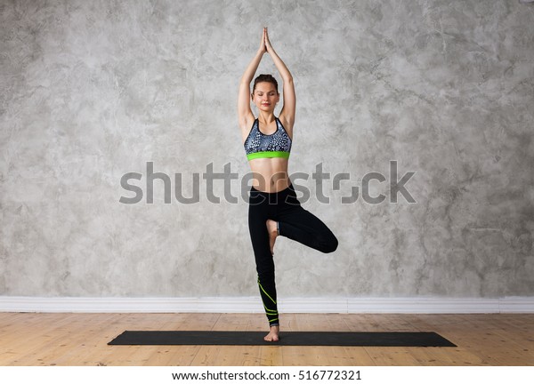 Young woman practicing yoga\
Tree pose, Vrikshasana against texturized wall / urban background \
