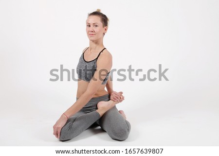 Young woman practicing yoga,standing in exercise leaning forward to straight legs, holding hands,toes,bharadvadjasana pose, balance workout,sportswear, pants,short,studio,white grey background