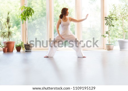 Young Woman praticing tai chi chuan in the gym. Chinese management skill Qi's energy.