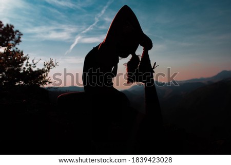 Young woman prating yoga silhouette mountain sunset sunrise pink orange blue sky tree girl foreground posing lookout mountain Colorado beautiful gorgeous workout exercise in evening vacation fitness 