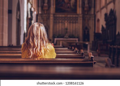 Young Woman Praying And Meditating In Church. Belief In Jesus Christ. Catholic Cathedral With Symbol Of Religion