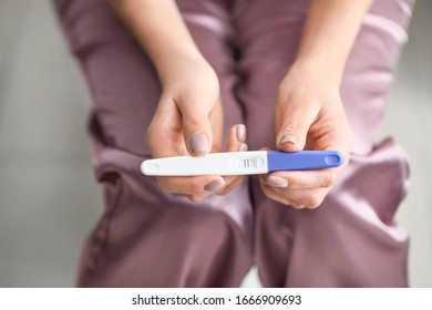 Young Woman With Pregnancy Test In Bathroom, Closeup