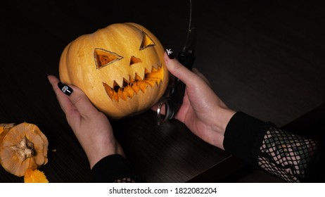 Young woman prepares a pumpkin for Halloween Cuts out the eyes Celebration