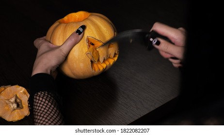 Young woman prepares a pumpkin for Halloween Cuts out the eyes Celebration