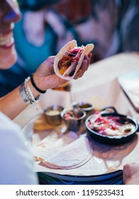 Young Woman Preparing And Eating Mexican Food In A Street Restaurant.  Mexican Tacos, Nachos And Wings.