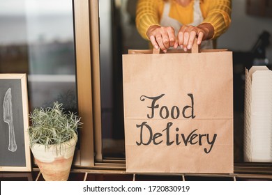 Young woman preparing food delivery inside ghost kitchen during quarantine isolation time - Take away meal for online order - Sustainable and healthy food concept - Focus on hands