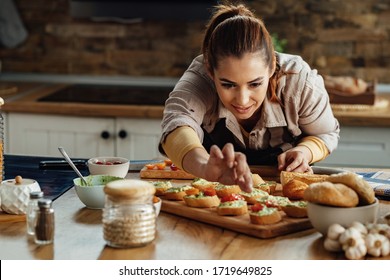 Young woman preparing food and making bruschetta in the kitchen. 