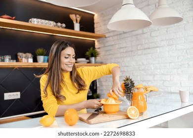 Young woman preparing fresh orange juice in her modern kitchen. Healthy lifestyle concept.Making some videos for her channel. - Powered by Shutterstock