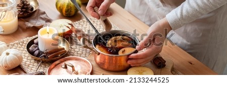 Young woman preparing hot autumn drink: mulled wine with spices, fruits. Natural ingreduents: cinnamon, anise, cardamon, clove, apple, orange. Cozy home atmosphere. Banner