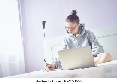 A young woman is preparing for an interview for work. Prepare for exam. The light from the window.  Quiet morning light. Lilac pastel colors.. Laptop.