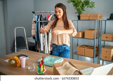 Young Woman Are Preparing A Package For Delivery To Clients. Online Clothing Store. Small Business Owner. Working Woman At Her Store. She Wearing Casual Clothing And Preparing New Orders For Today