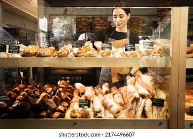 Young woman preparing pastry for sale in supermarket bakery department. Bakery female seller. - Powered by Shutterstock