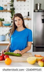 Young Woman Preparing Salad In The Kitchen And Looking At Camera