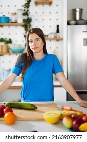 Young Woman Preparing Salad In The Kitchen And Looking At Camera