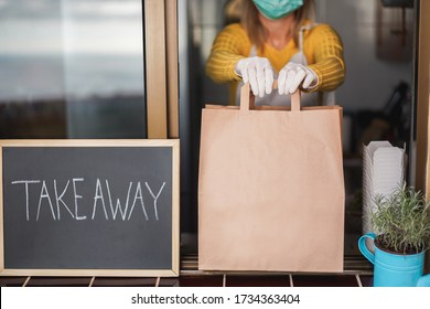 Young woman preparing takeaway organic food inside restaurant during Coronavirus outbreak time - Worker inside kitchen cooking food for online delivery service - Focus on hands