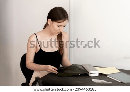 a young woman prints new tattoo sketch on a paper using a printing machine in studio