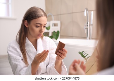 Young Woman With Problem Of Dandruff In Bathroom