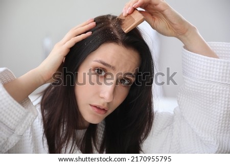 Young woman with problem of dandruff combing hair in bathroom Foto stock © 