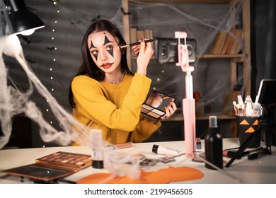 Young woman and professional beauty make up artist vlogger recording makeup on Halloween tutorial in home studio to share on website or social media. Blogger use mobile phone camera on tripod - Shutterstock ID 2199456505