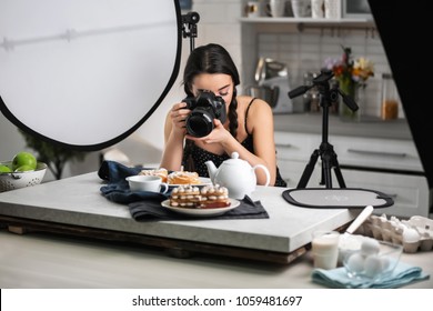 Young Woman With Professional Camera Taking Food Photo In Studio