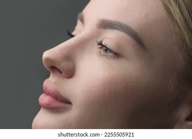 Retrato de perfil de mujer joven sobre fondo gris. Mujer de belleza, niña modelo cara a cara. Medicina estética. Modelo rubio con piel perfecta