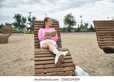 A young woman with a prosthetic leg reading outdoors - Powered by Shutterstock