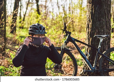 Young woman in protective mask from environmental pollution riding mountain bike on forest road. Cyclist Riding Bike on Trail in park. Face pollution mask smog dust protection. Coronavirus Covid 19.