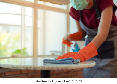 Young Woman In Protective Mask And Gloves Cleaning Up Table With Alcohol To Prepare To Open Coffee Shop Or Restaurant After Coronavirus Or Covid Unlock For Customer As New Normal Lifestyle