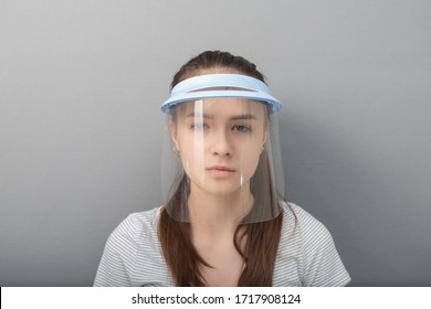 Young woman in a protective mask screen with a visor on a gray background