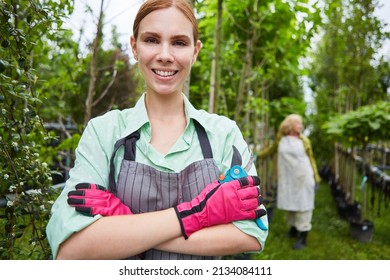 Young Woman As A Proud Gardener Trainee With Secateurs In The Nursery Of The Nursery