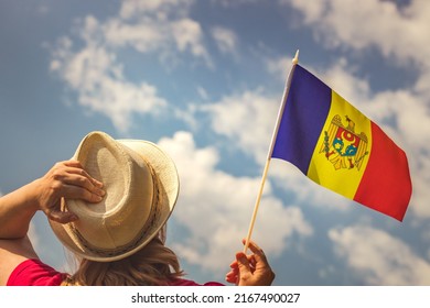 A young woman proudly holds the flag of Moldova above her head while holding up her hat with her other hand, Concept of the holiday of independence and patriotic events
