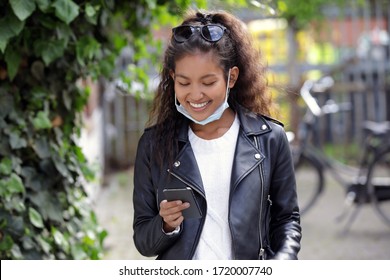 Young woman with pulled down face mask, checking her phone

