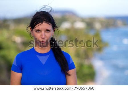 Young woman pulling faces pouting at the camera as she poses overlooking the coastline on Diamond head, Oahu, Hawaii
