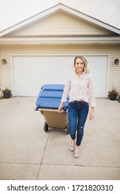 Young Woman Pulling Garbage Can Down Driveway